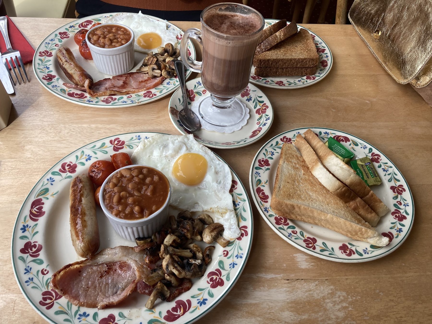 English breakfasts with beans, sausage, mushrooms and toast, and a hot chocolate